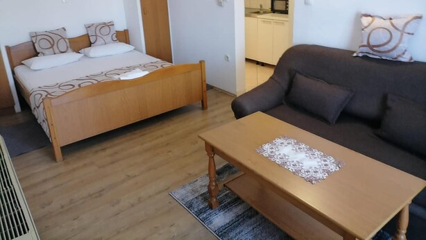 A bedroom with a bed, a wooden table, and a sofa. - Apartments Libertas - One Bedroom Apartment With Terrace and Sea View- (Rogoznica)