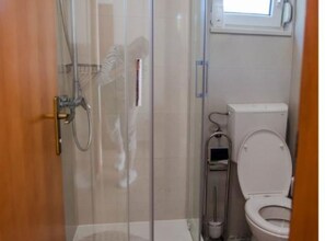 A bathroom with a glass shower enclosure, a toilet, and a towel rack. - One Bedroom Apartment With sea Wiev 3 (Gradac)