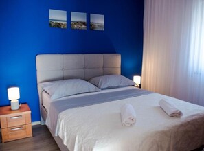 A hotel room with a bed, a bedside table with a lamp, and a nightstand. - One Bedroom Apartment With sea Wiev 3 (Gradac)