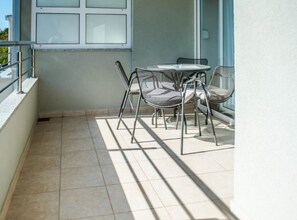A balcony with a tiled floor, a glass door, and a table with chairs. - One Bedroom Apartment With sea Wiev 3 (Gradac)