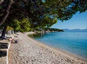 A beach with a clear view of the sea, a sandy shore, and a tree providing shade. - One Bedroom Apartment With sea Wiev 3 (Gradac)