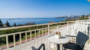 Un balcone con vista sul mare, un tavolo rotondo con una sedia e un piccolo bouquet di fiori.