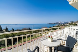 Ein Balkon mit Meerblick, ein runder Tisch mit einem Stuhl und eine kleine Blumenkomposition.