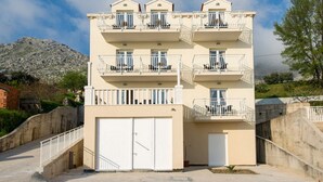Un edificio a più piani con balconi, un garage e una scalinata che conduce all'ingresso.