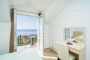 Ein Hotelzimmer mit Balkon, einem Bett, einem Schreibtisch und einem Spiegel.
