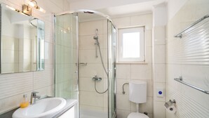 Un bagno moderno con cabina doccia in vetro, lavandino bianco e water.
