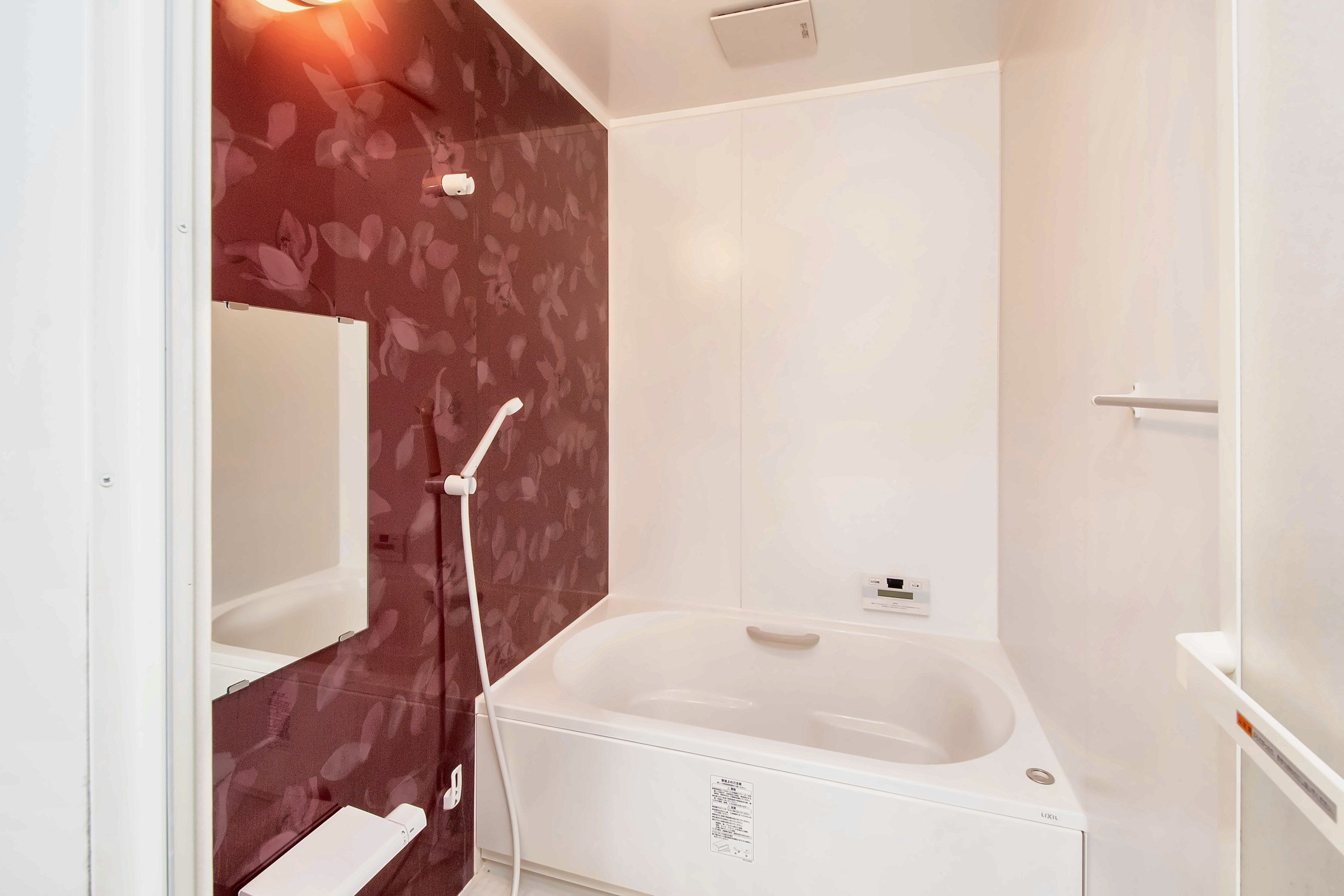 A bathroom with a white bathtub, a shower, and a mirror.