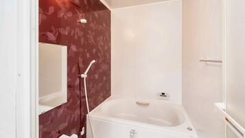 A bathroom with a white bathtub, a shower, and a mirror.