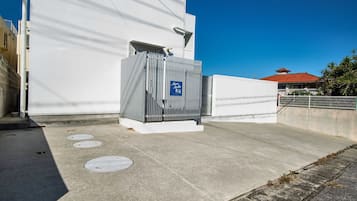 Un bâtiment à la façade blanche, une structure métallique avec une enseigne bleue, et un ciel d’un bleu limpide.