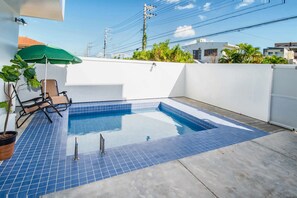 A rooftop swimming pool with blue tiles, a green umbrella, and a chair. - Marestella Zanpa (Nakagami-gun)