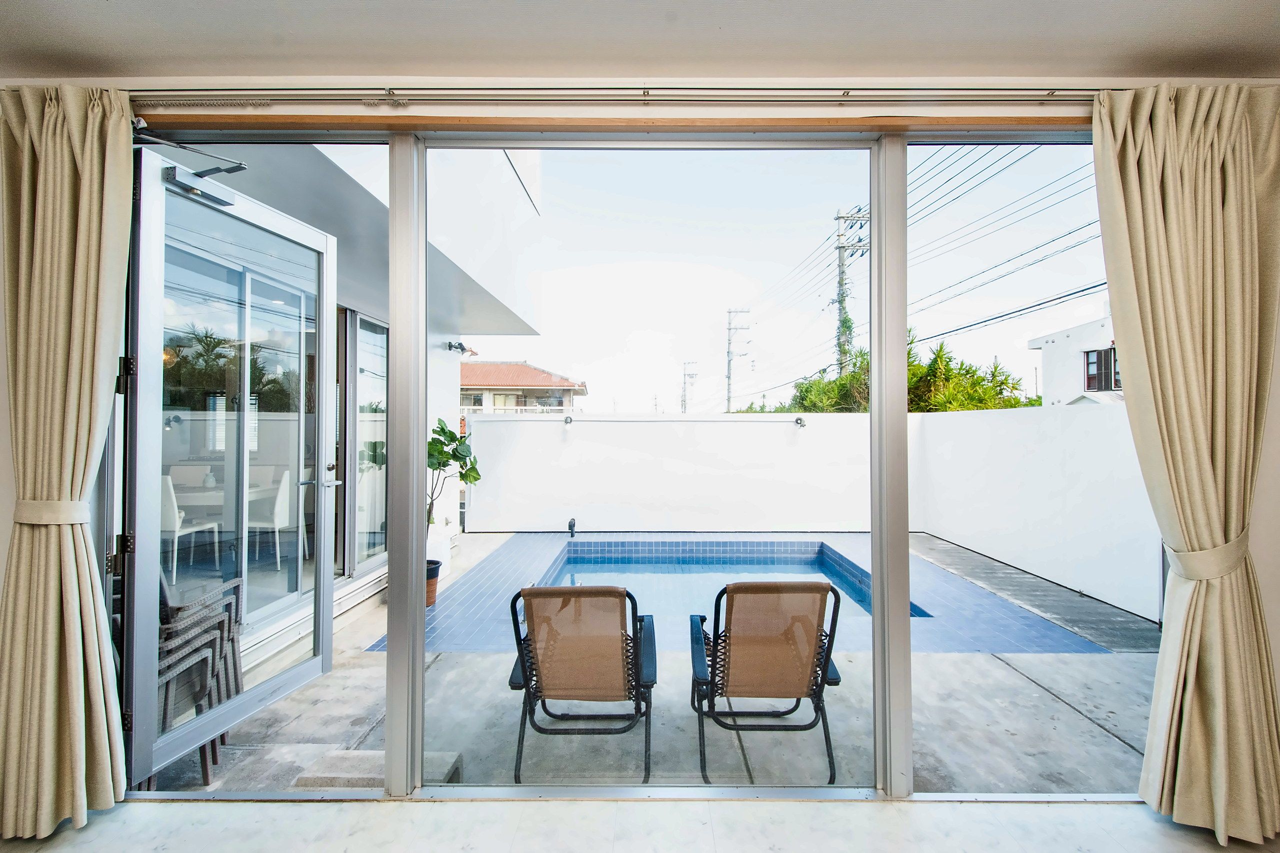 A sliding glass door leading to a balcony with a pool and two chairs.