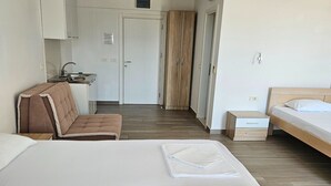 Una habitación de hotel con una cama, una silla, una mesita y un kitchenette.