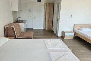 Ein Hotelzimmer mit Bett, einem Sessel, einem kleinen Tisch und einer Küchenzeile.