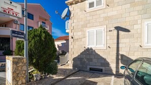 Un carrer estret amb un edifici de pedra, un cotxe aparcat i un cartell d'un estudi.