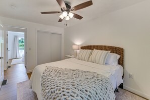 A bedroom with a bed, a ceiling fan, a nightstand, and a window.