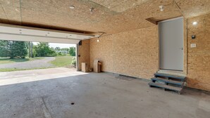 Un garaje con piso de concreto, paredes de madera y una puerta grande.