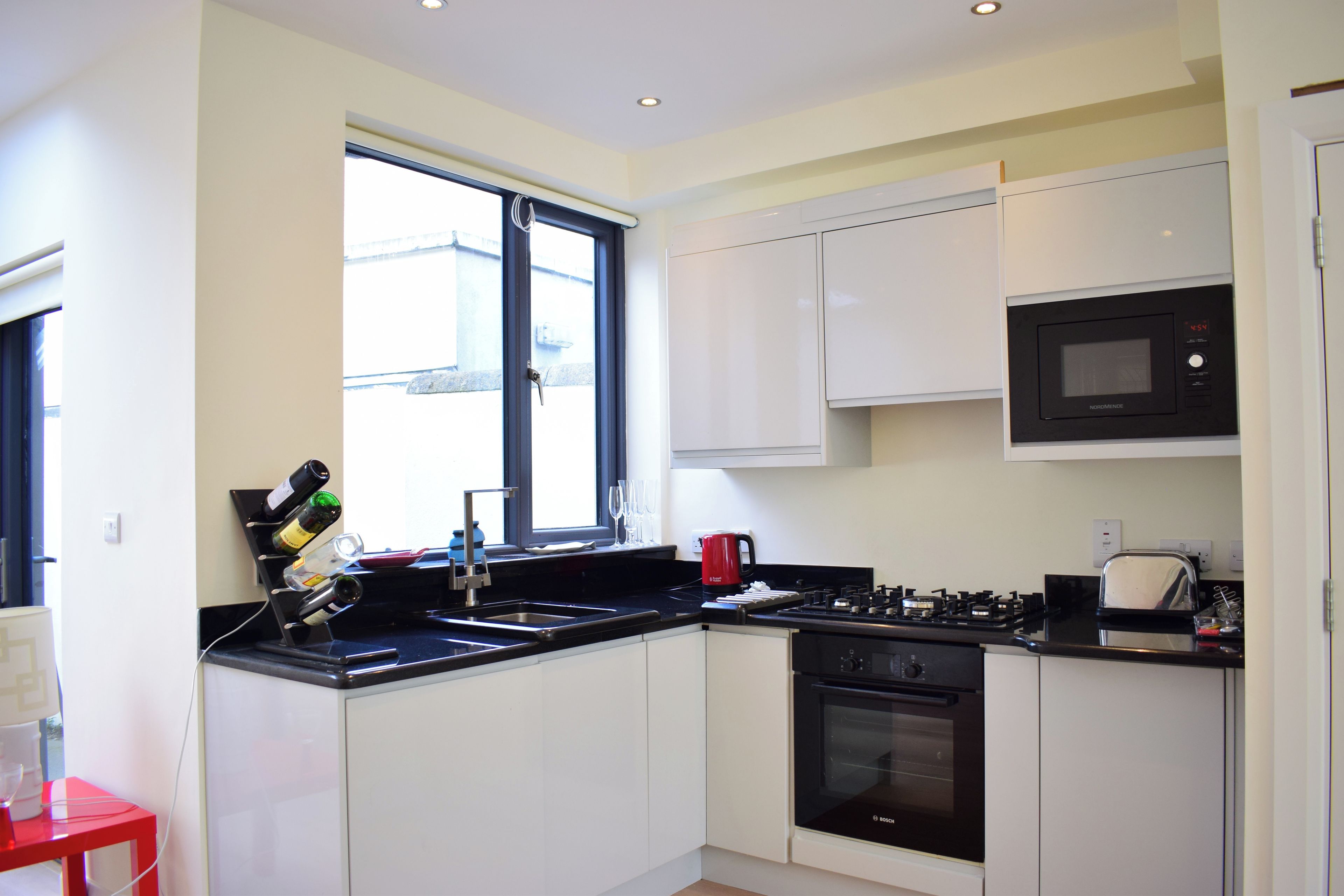 A modern kitchen with white cabinets, a black stove, and a microwave.