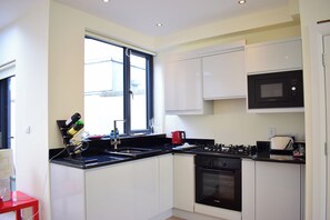 A modern kitchen with white cabinets, a black stove, and a microwave. - Bright home close to Dublin city centre- sleeps 4! (Dublin)
