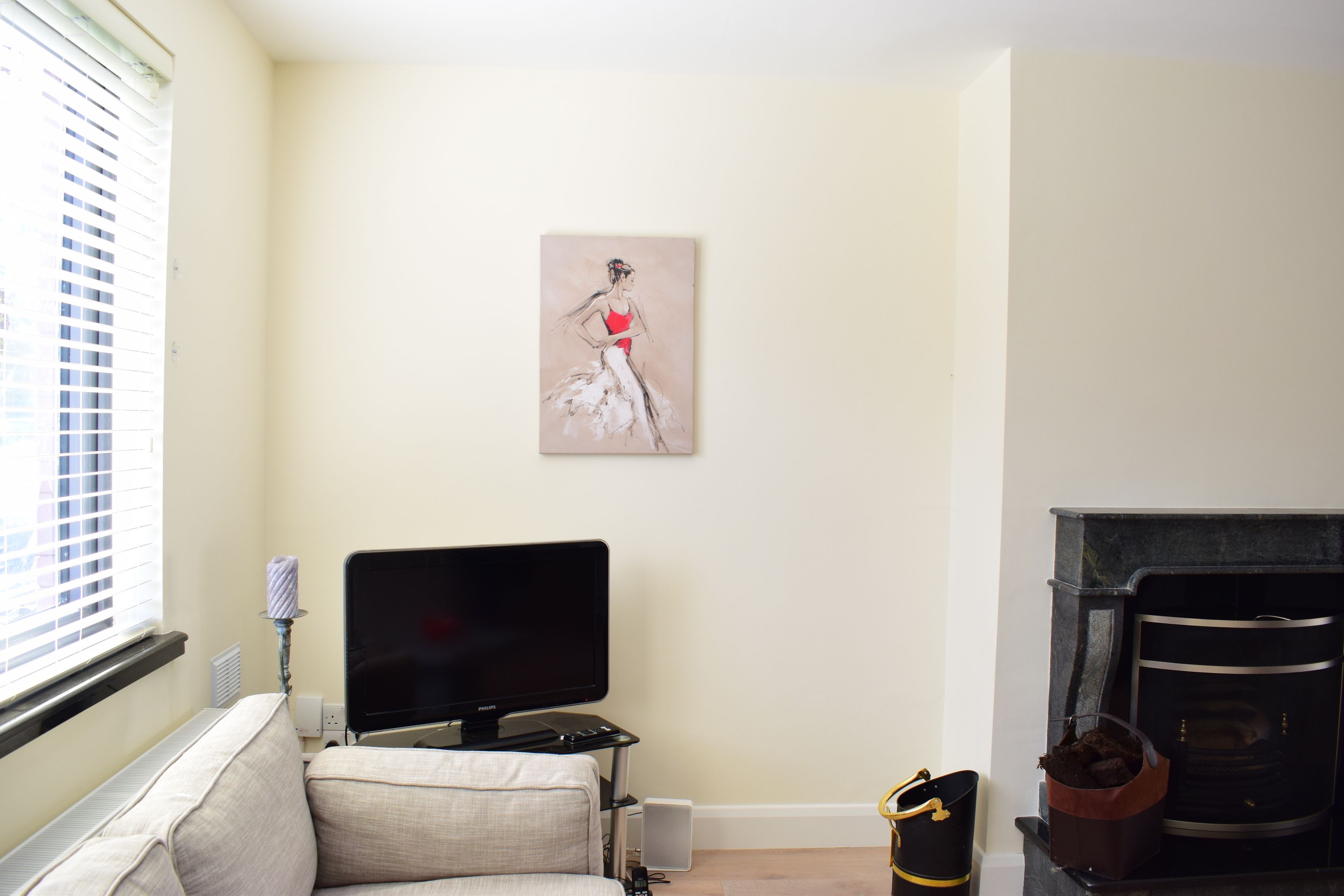 A living room with a flat-screen TV, a sofa, a fireplace, and a painting on the wall.
