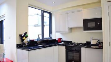 A modern kitchen with white cabinets, a black stove, and a microwave.