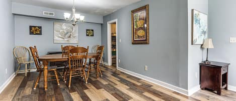 Un comedor con mesa y sillas de madera, una lámpara de araña y obras de arte en las paredes.