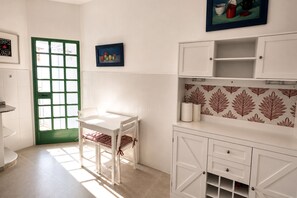 Una cocina con muebles blancos, una puerta verde y una ventana con vistas.