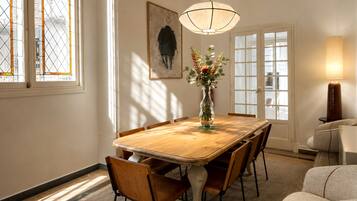 Comedor con una mesa de madera, sillas, un jarrón con flores, un cuadro en la pared y una ventana con vistas.