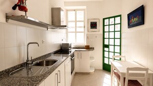 Une cuisine avec des meubles blancs, un plan de travail en granit, un évier, un four à micro-ondes et une porte dont le cadre est vert.