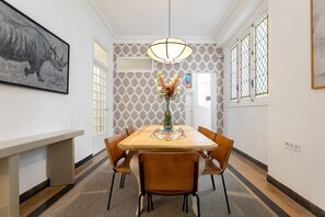 Un coin repas comprenant une table en bois, six chaises, un vase avec des fleurs et un luminaire suspendu.