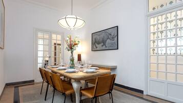Une salle à manger avec une table en bois mise pour quatre personnes, entourée de chaises, un vase rempli de fleurs et un tableau accroché au mur.