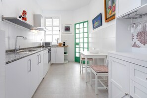 Cozinha moderna com armários brancos, micro-ondas, pia e porta verde.
