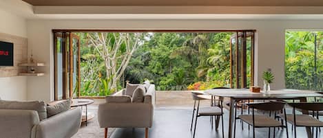 A modern living room with a sofa, coffee table, and dining area with chairs and a table.