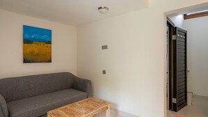 Un salon avec un canapé gris, une petite table en bois et un tableau accroché au mur.