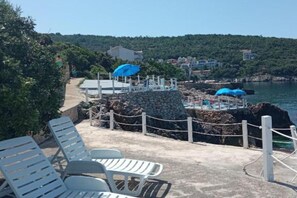 A coastal area with a stone wall, seating, and a view of the sea and hills. - Apartments Lux Lukić Utjeha - One bedroom apartment (Utjeha)