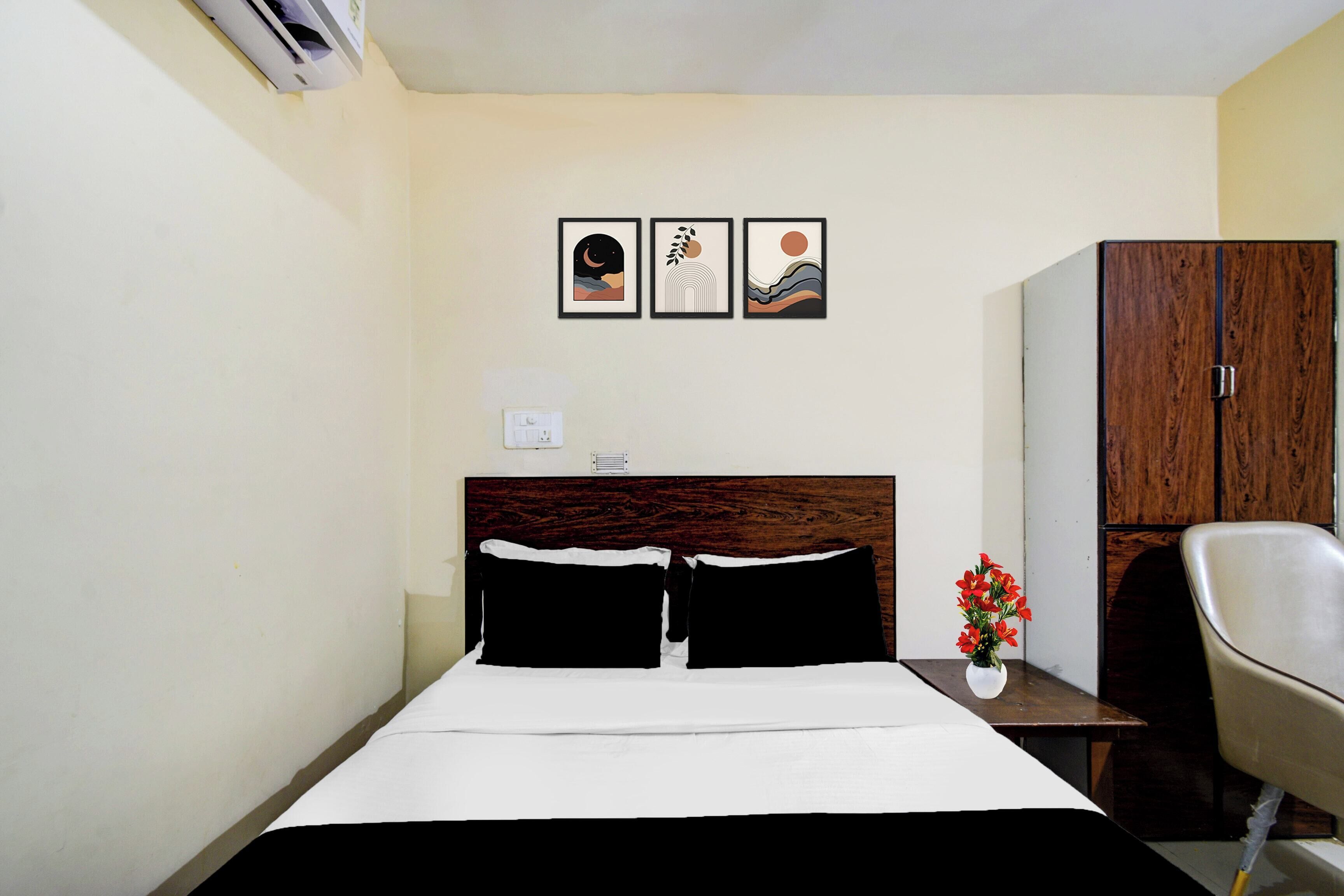 Habitación de hotel con cama, mesita de noche, una silla, armario y tres cuadros en la pared.