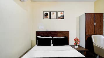 Habitación de hotel con cama, mesita de noche, una silla, armario y tres cuadros en la pared.