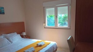 A hotel room with a bed, a window, a chair, and a nightstand with a lamp. - Apartments Lux Lukić Utjeha - One bedroom apartment (Utjeha)