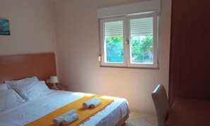 Ein Hotelzimmer mit einem Bett, einem Fenster, einem Sessel und einem Nachttisch mit einer Lampe.