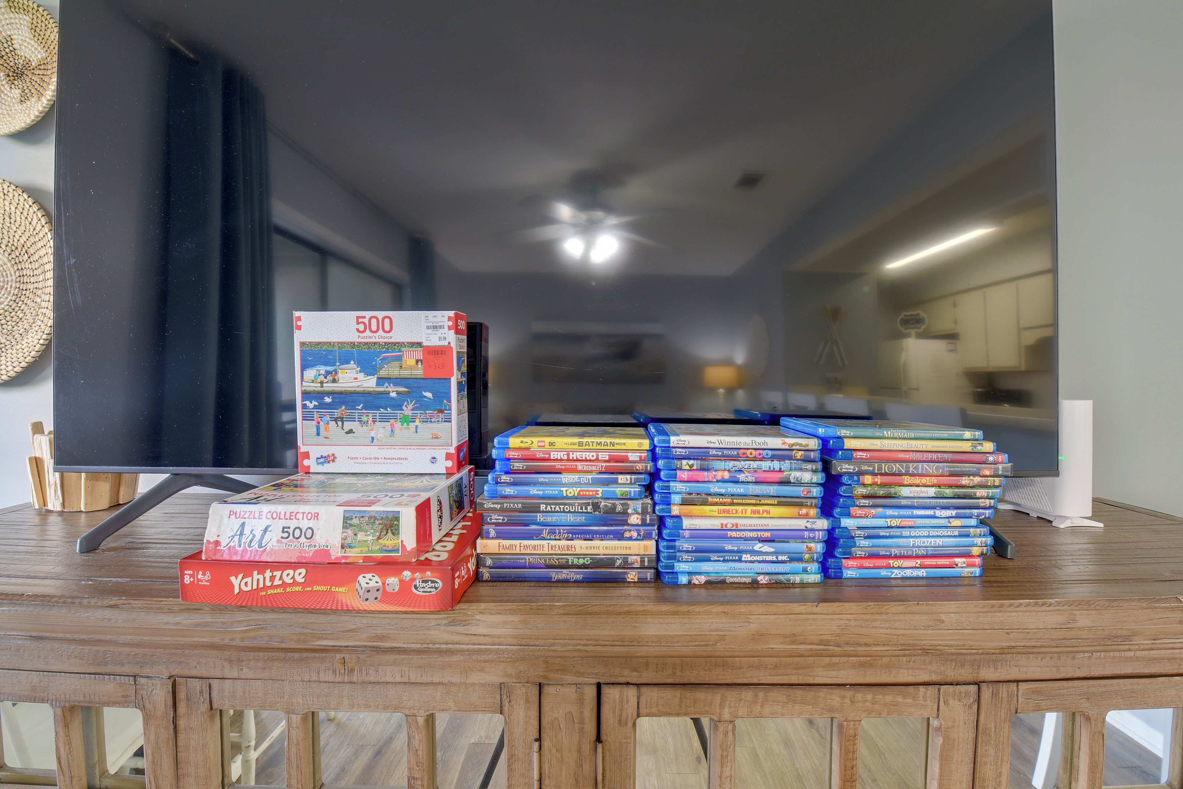 A collection of DVDs and a puzzle box on a wooden table in a room with a modern interior.