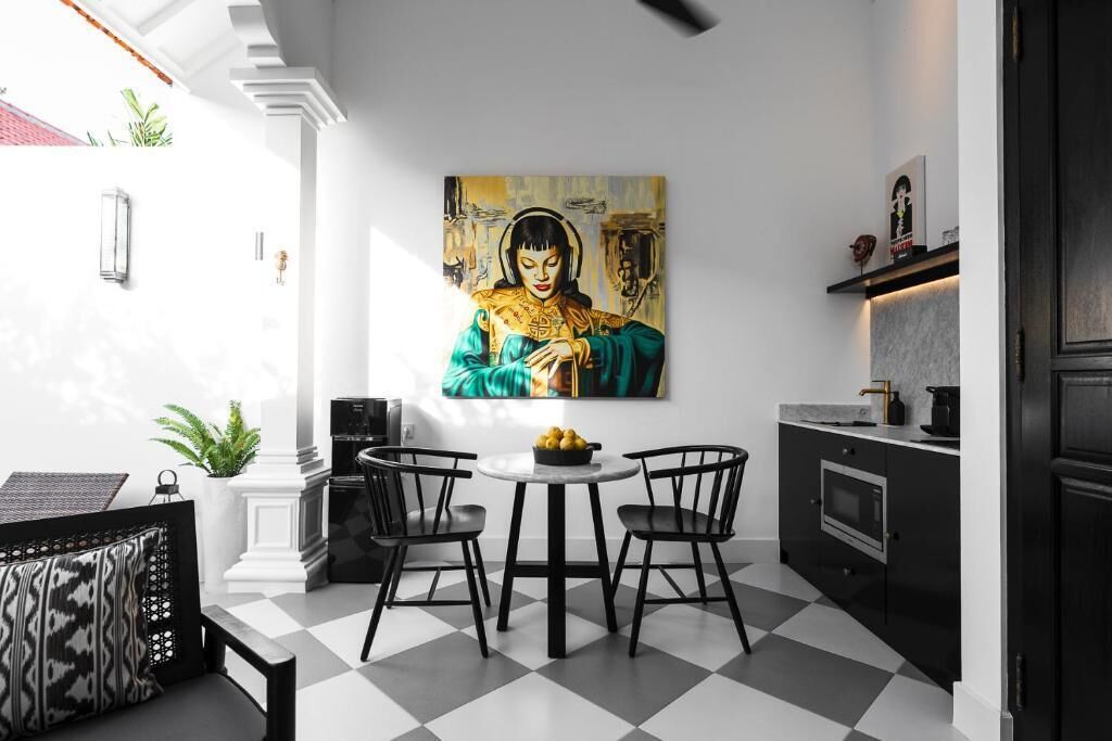 Una cocina moderna con piso a cuadros, una mesa de comedor con sillas, un cuadro en la pared y un mueble negro con microondas.