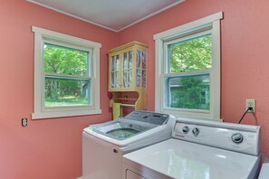 A laundry room with two washing machines, a dryer, and a cabinet with a window. - Boating, Bonfires & Lake Views! Michigan Getaway (Ellsworth)