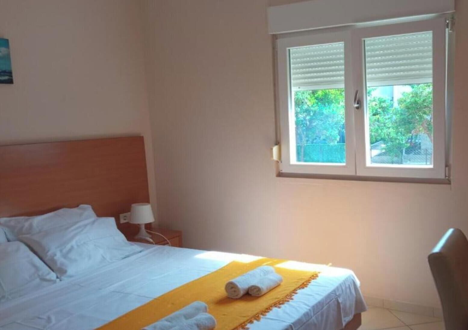 Ein Hotelzimmer mit einem Bett, einem Fenster, einem Sessel und einem Nachttisch mit einer Lampe.