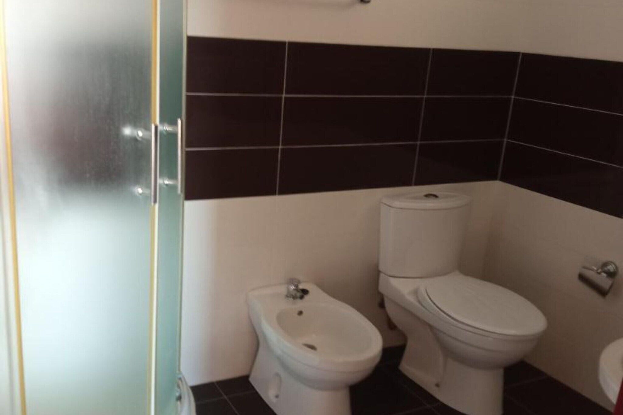 Ein Badezimmer mit einer Bio-Toilette, einer Toilette und einer Glasabtrennung.