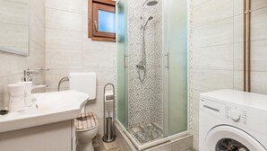 Een moderne badkamer met douche, toilet, wastafel en wasmachine.