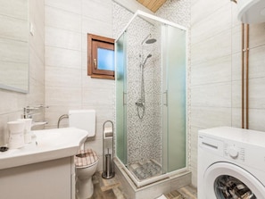 Ein modernes Badezimmer mit Dusche, Toilette, Waschbecken und Waschmaschine.