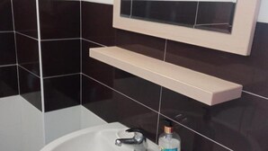 Ein Badezimmer mit einem weißen Waschbecken, einem Spiegel darüber und einem Regal.