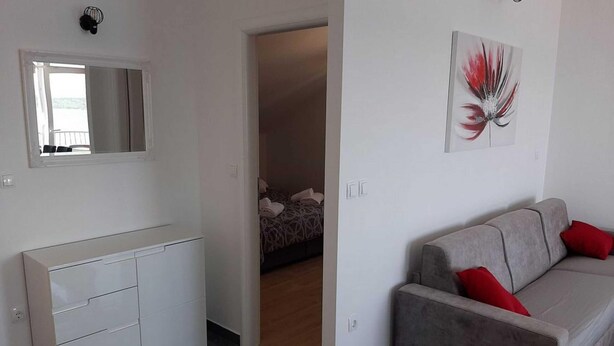 A modern living room with a grey sofa, a white cabinet, and a painting on the wall. - Apartments Dobrila - One Bedroom Apartment With Terrace and sea View - B1 (Jelsa)