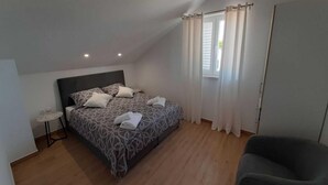 A bedroom with a bed, a small table, a chair, and a window with curtains. - Apartments Dobrila - One Bedroom Apartment With Terrace and sea View - B1 (Jelsa)