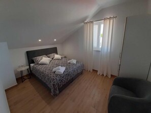 A bedroom with a bed, a small table, a chair, and a window with curtains. - Apartments Dobrila - One Bedroom Apartment With Terrace and sea View - B1 (Jelsa)