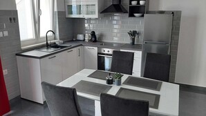 A modern kitchen with a central island, built-in appliances, and a window providing natural light. - Apartments Dobrila - One Bedroom Apartment With Terrace and sea View - B1 (Jelsa)